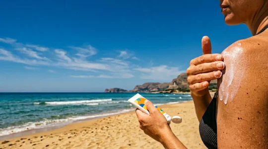 Applicazione di crema solare su pelle esposta al sole intenso estivo mediterraneo