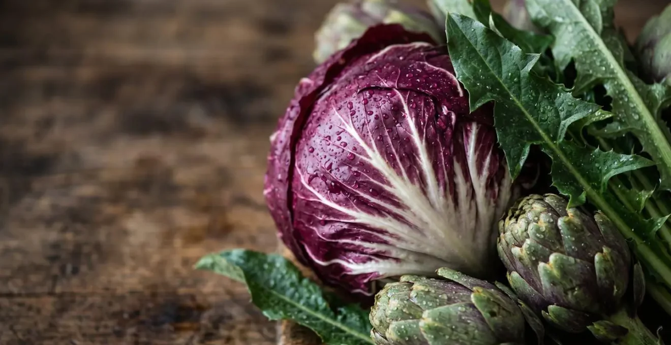 Verdure amare italiane fresche come carciofi, radicchio e cicoria su tagliere di legno